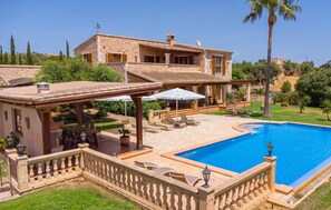 Eine Steinvilla mit Swimmingpool, Außenbereich mit Sitzgelegenheiten und überdachter Terrasse.