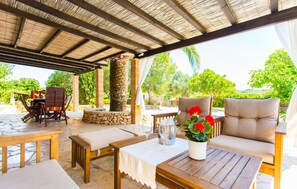 Un espace extérieur aménagé avec du mobilier en bois, un pilier en pierre et une vue sur une végétation luxuriante.