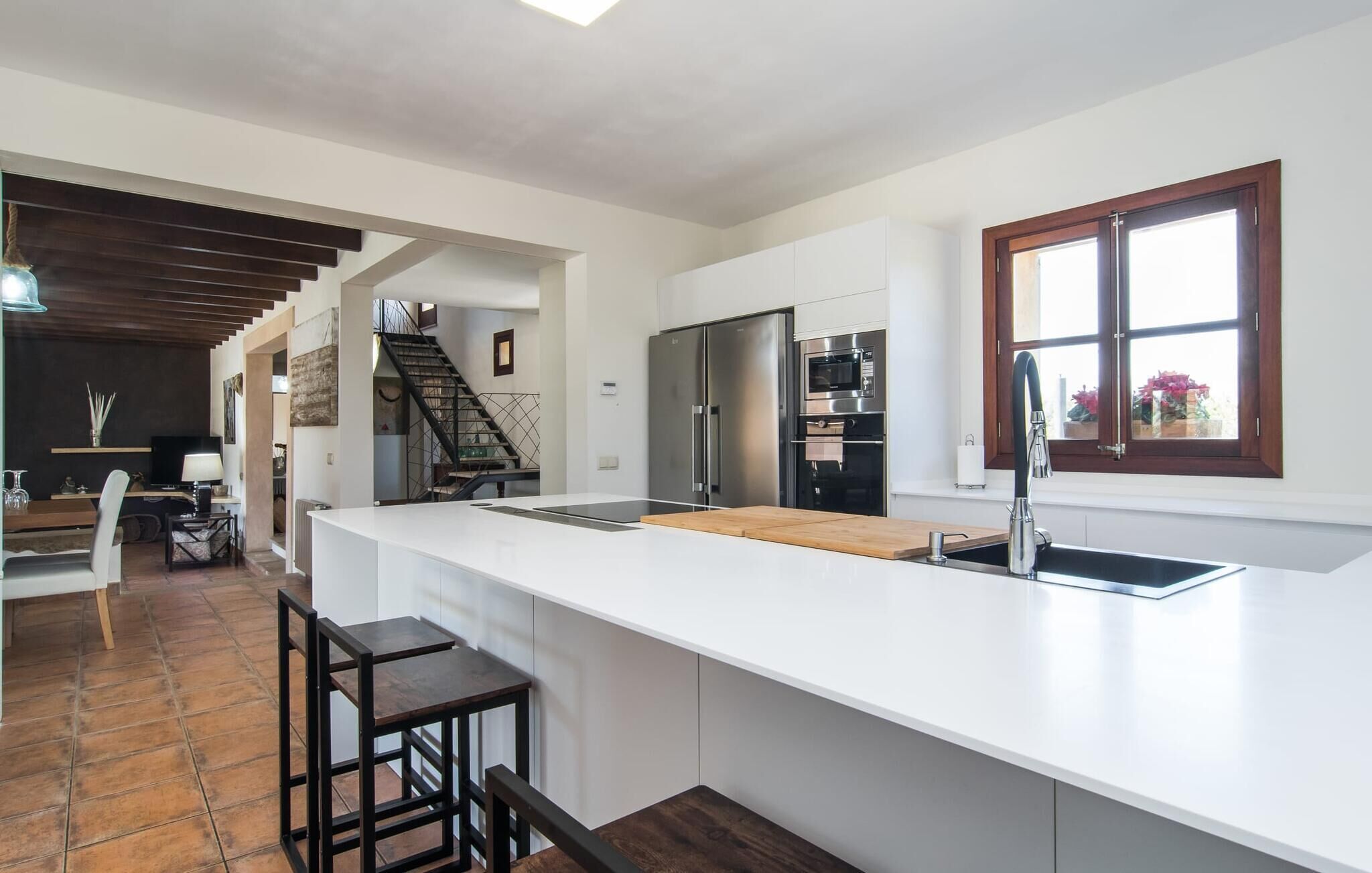 A modern kitchen with a large island, stainless steel appliances, and a window with a view.