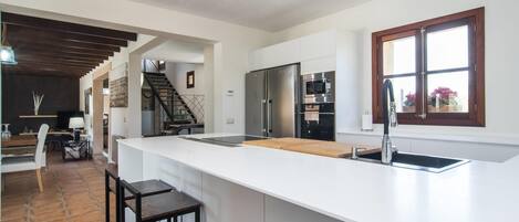 A modern kitchen with a large island, stainless steel appliances, and a window with a view.