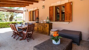 An outdoor dining area with wooden furniture, a table set with wine glasses, and a decorative vase with flowers. - Lovely home in Buger with private swimming pool, can be inside or outside (Buger)