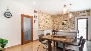 A modern kitchen with a stone wall, wooden cabinetry, and a dining area with a marble table and leather chairs. - Lovely home in Buger with private swimming pool, can be inside or outside (Buger)