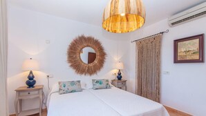A bedroom with a bed, two bedside tables, a wall-mounted mirror, a hanging light fixture, a macrame curtain, and a framed picture on the wall. - Amazing home in Portocolom with private swimming pool, can be inside or outside (Portocolom)
