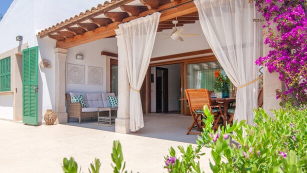 A covered outdoor seating area with a table and chairs, a ceiling fan, and a view of the interior through a glass door. - Amazing home in Portocolom with private swimming pool, can be inside or outside (Portocolom)