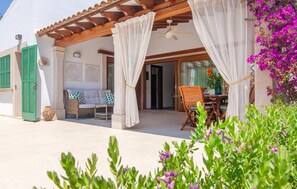 A covered outdoor seating area with a table and chairs, a ceiling fan, and a view of the interior through a glass door. - Amazing home in Portocolom with private swimming pool, can be inside or outside (Portocolom)