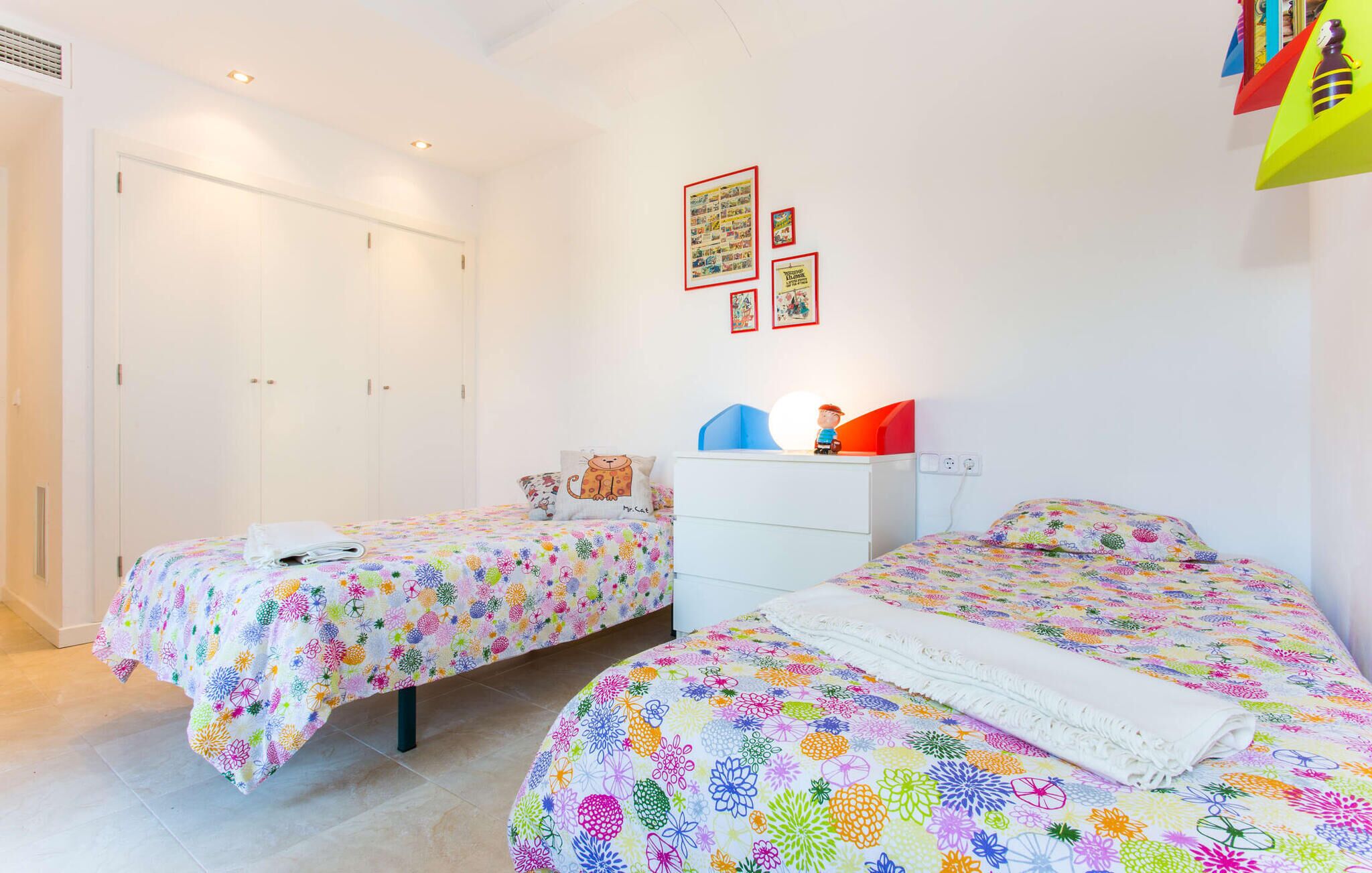 A bedroom with two beds, a wardrobe, and a dresser.
