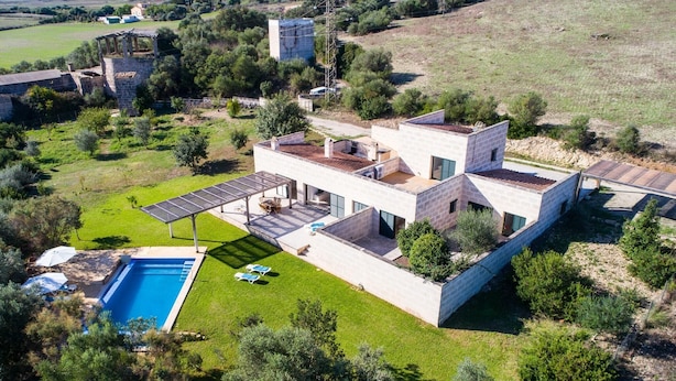 Una moderna casa a due piani con piscina, area salotto esterna e patio coperto.