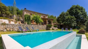 A rectangular swimming pool with a stone wall and tiled edge, surrounded by lounge chairs and a stone building with a tiled roof. - Gorgeous home in Campanet with private swimming pool, can be inside or outside (Campanet)