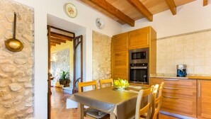 A kitchen with wooden cabinets, a stove, and a coffee maker. - Gorgeous home in Campanet with private swimming pool, can be inside or outside (Campanet)