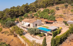 Eine moderne Villa mit Swimmingpool, Sitzgelegenheiten im Freien und Blick auf die umliegende Landschaft.