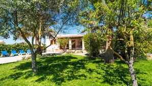 Eine Villa mit Garten, Pool und Terrasse.