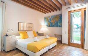 A bedroom with a bed, a nightstand, a lamp, a map on the wall, and a door leading to an outdoor area. - Beach front home in Cala Millor (Cala Millor)