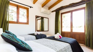 A room with two beds, a mirror, an air conditioning unit, and a large window with curtains. - Beautiful home in Pollenca with private swimming pool, can be inside or outside (Pollenca)