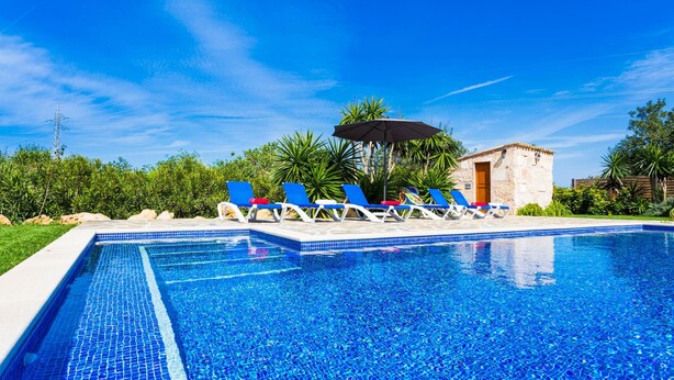 A swimming pool with blue tiles, surrounded by lounge chairs and a small building. - Beautiful home in Pollenca with private swimming pool, can be inside or outside (Pollenca)