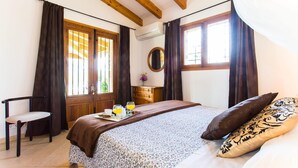 A bedroom with a bed, a chair, a dresser, and a window with curtains. - Beautiful home in Pollenca with private swimming pool, can be inside or outside (Pollenca)