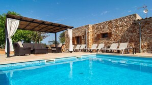 Piscina com espreguiçadeiras e um pergolado.