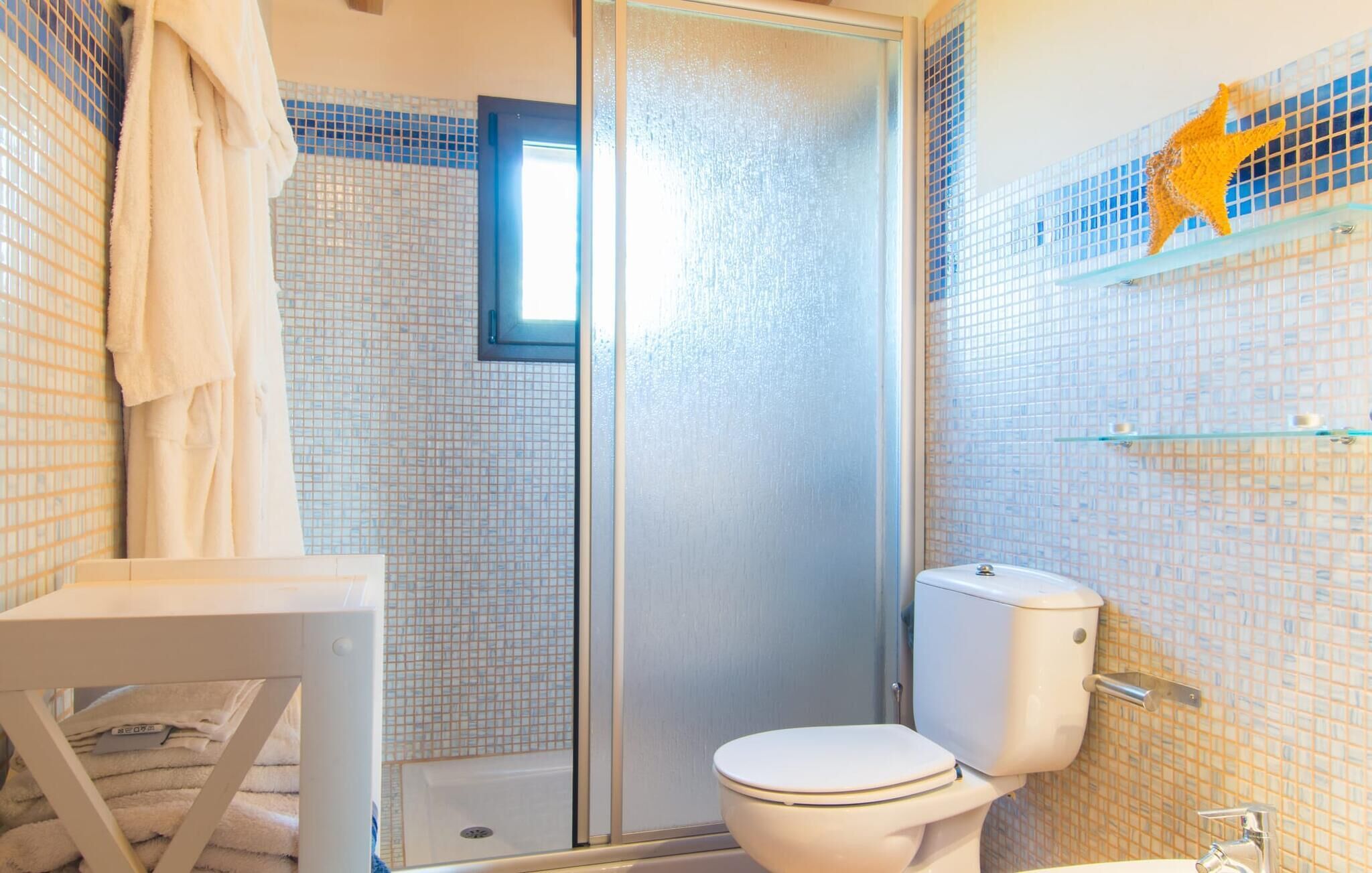 Un baño con cabina de ducha de vidrio, inodoro y lavamanos.