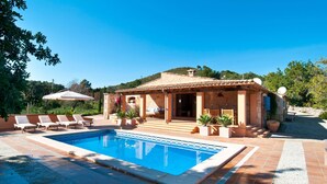 Una villa con piscina, area relax esterna e facciata in pietra.