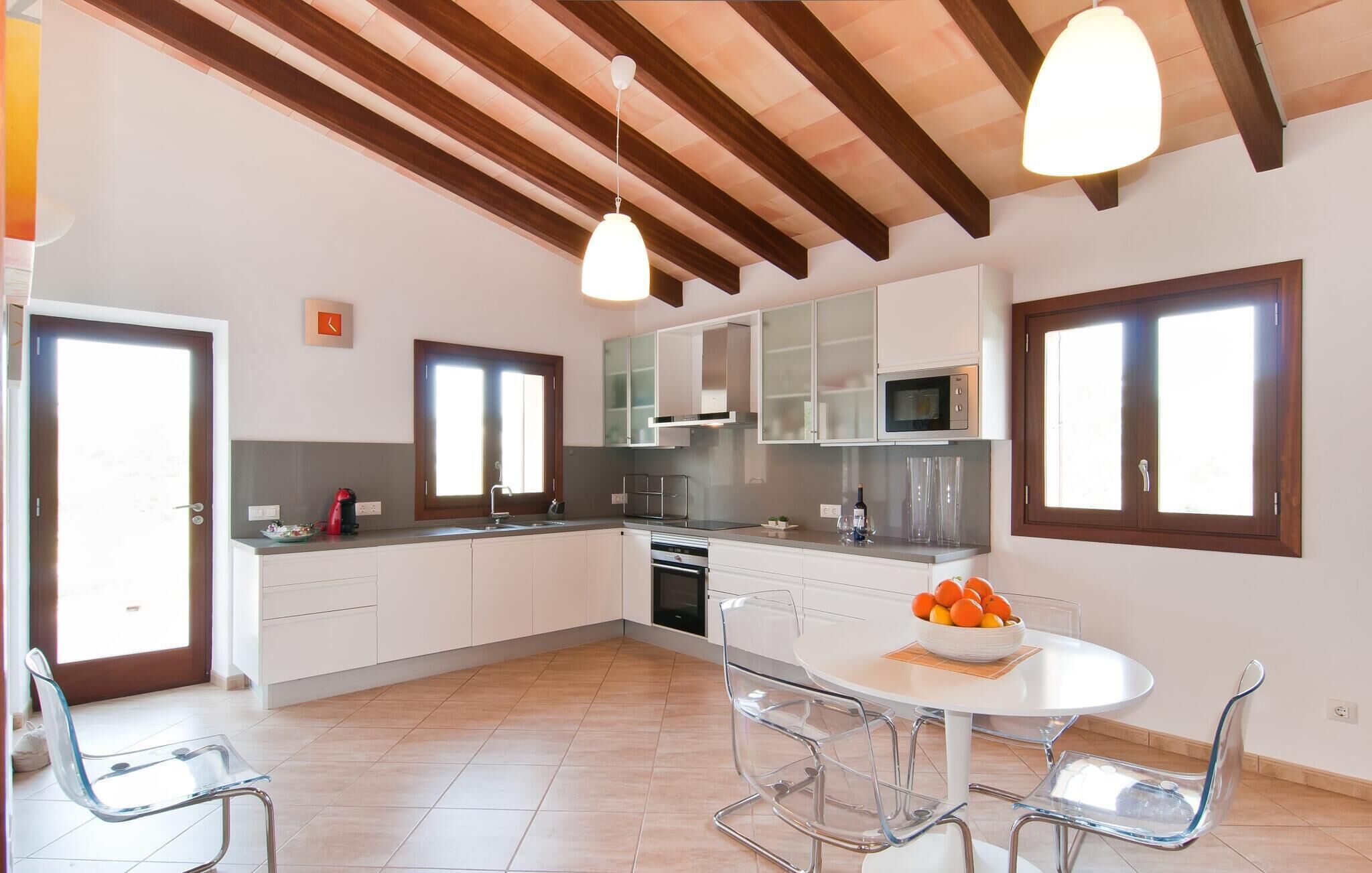 Una cucina moderna con mobili bianchi, un forno a microonde e un'area da pranzo con un tavolo rotondo e sedie.