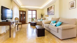 A living room with a television, a wooden cabinet, a sofa with cushions, a coffee table, and a lamp. - Cozy home in Manacor with private swimming pool, can be inside or outside (Manacor)