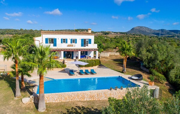 A two-story house with a swimming pool, surrounded by palm trees and a mountainous landscape. - Amazing home in Sant Llorenc (Sant Llorenc)