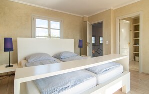 A bedroom with a bed, bedside lamps, a wardrobe, and a door leading to another room. - Amazing home in Sant Llorenc (Sant Llorenc)