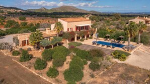 A villa with a swimming pool, surrounded by landscaped gardens and a mountainous backdrop. - Amazing home in Cales de Mallorca (Cales de Mallorca)