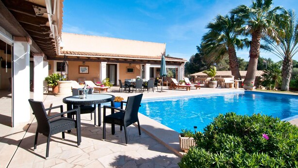A poolside area with lounge chairs, a table, and a view of a swimming pool. - Beautiful home in Portocolom (Portocolom)