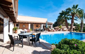 A poolside area with lounge chairs, a table, and a view of a swimming pool. - Beautiful home in Portocolom (Portocolom)