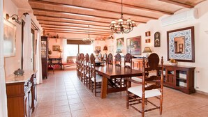 A spacious dining area with a long wooden table and chairs, a chandelier, and various wall decorations. - Beautiful home in Portocolom (Portocolom)