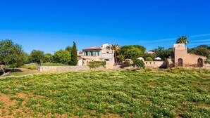 A Mediterranean-style villa with a garden, stone walls, and a clear blue sky. - Beautiful home in Cas Concos des Cavalle (Cas Concos des Cavalle)