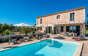 A stone building with a pool, outdoor seating, and a clear blue sky. - Lovely home in Ses Salines with private swimming pool, can be inside or outside (Ses Salines)