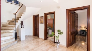 A spacious foyer with a marble staircase, wooden doors, and a potted plant. - Nice home in Alcudia with private swimming pool, can be inside or outside (Alcudia)