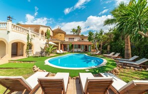 A pool area with lounge chairs, a well-maintained lawn, and a building with arched doorways. - Awesome home in Palma with private swimming pool, can be inside or outside (Palma)