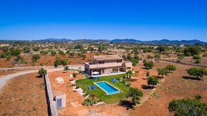 A modern villa with a swimming pool, surrounded by a landscaped garden and a view of distant hills. - Beach front home in Porto Cristo (Porto Cristo)