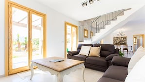 A modern living room with a staircase, a sofa, and a coffee table. - Beach front home in Porto Cristo (Porto Cristo)