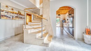 Ein modernes Interieur mit einer Wendeltreppe, einer Küche mit Edelstahlgeräten und einem großen Gemälde an der Wand.