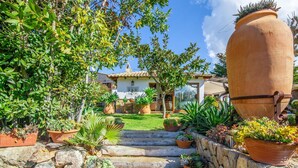 A garden pathway leading to a house with a tiled roof, surrounded by various potted plants and a large terracotta pot. - Stunning home in Esporles with private swimming pool, can be inside or outside (Esporles)