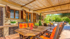 Eine Terrasse im Freien mit einem Holztisch, Stühlen, einem roten Laternen und Blumentöpfen.