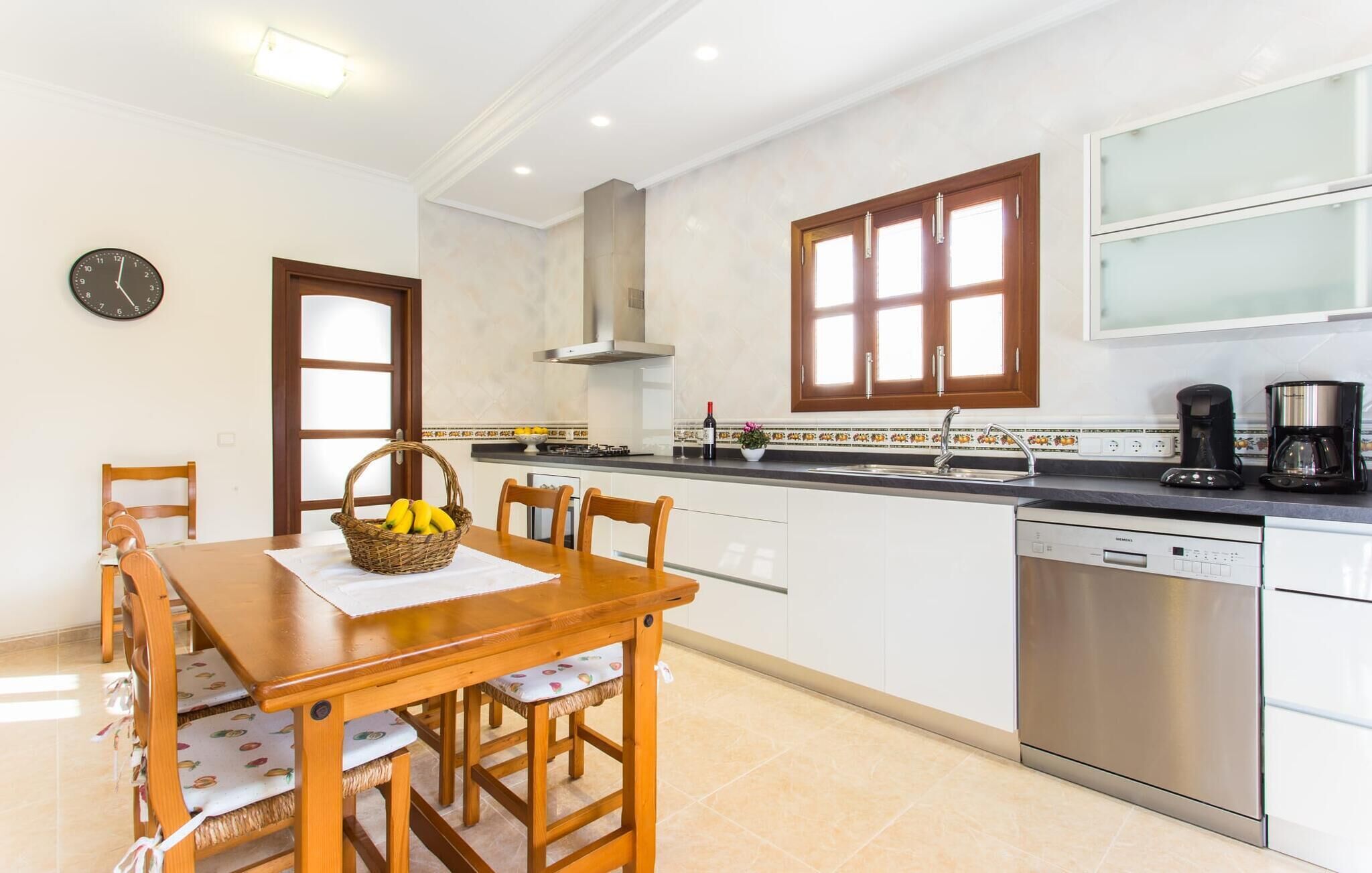 A modern kitchen with white cabinets, a stainless steel dishwasher, and a coffee maker.