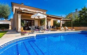A swimming pool with lounge chairs and umbrellas, a covered patio area, and a well-maintained garden. - Nice home in Sa Coma with private swimming pool, can be inside or outside (Sa Coma)