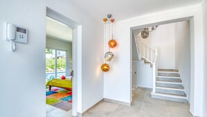 A modern interior with a staircase, a phone on the wall, and a view of a pool outside.