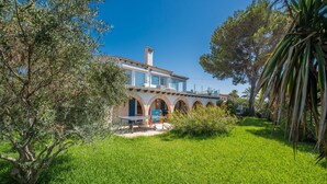 A Mediterranean-style villa with a spacious patio, arched windows, and lush greenery.