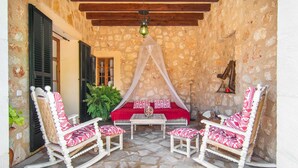 A cozy outdoor seating area with a stone wall, a wooden ceiling, and a canopy bed. - Nice home in Manacor with private swimming pool, can be inside or outside (Manacor)
