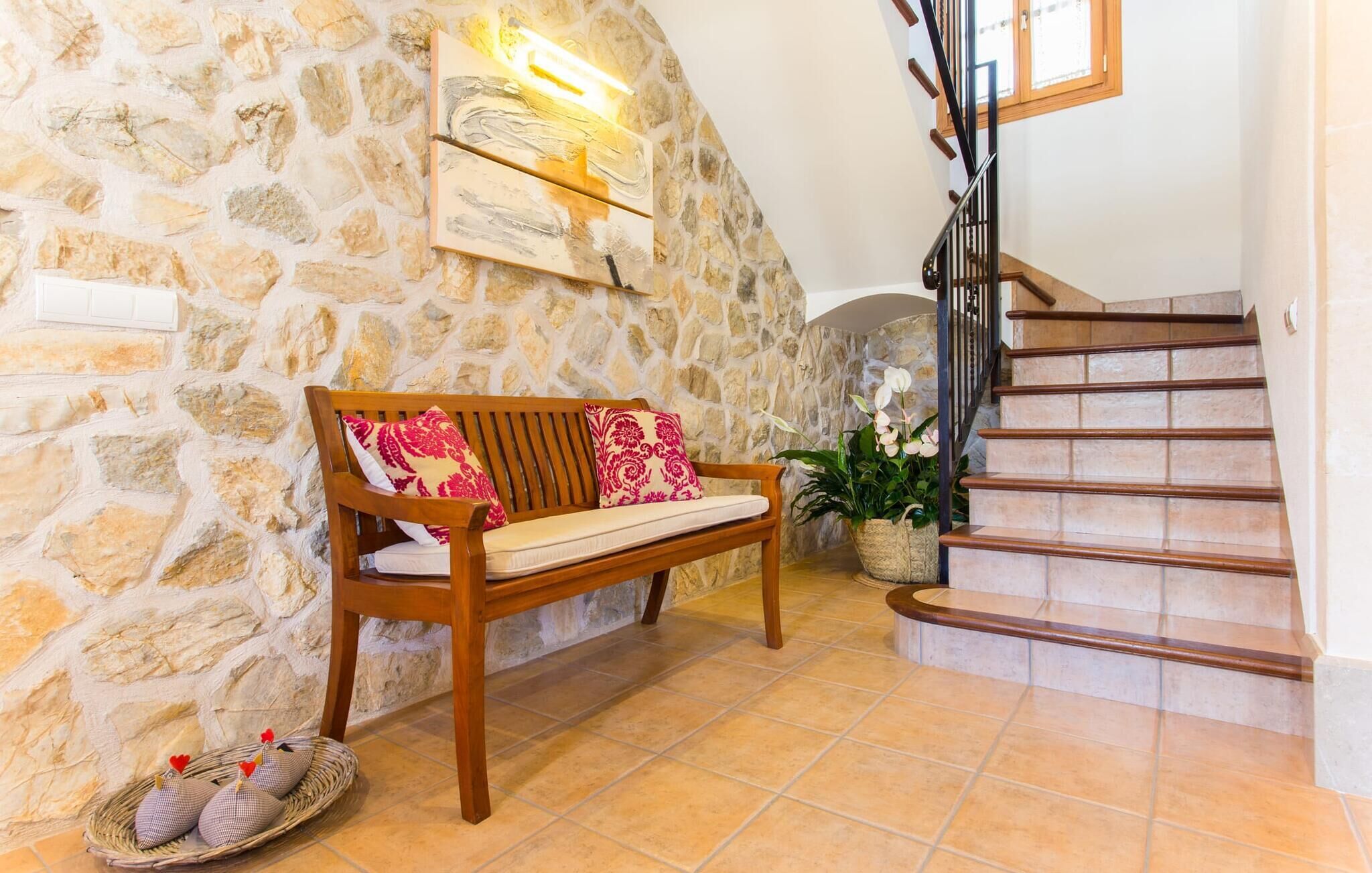 Un mur de pierre avec un banc en bois, un escalier et une plante en pot.