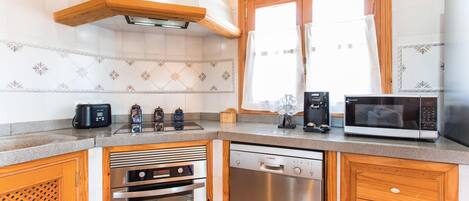 Una cocina moderna con lavavajillas Bosch, microondas, cafetera y tostadora.