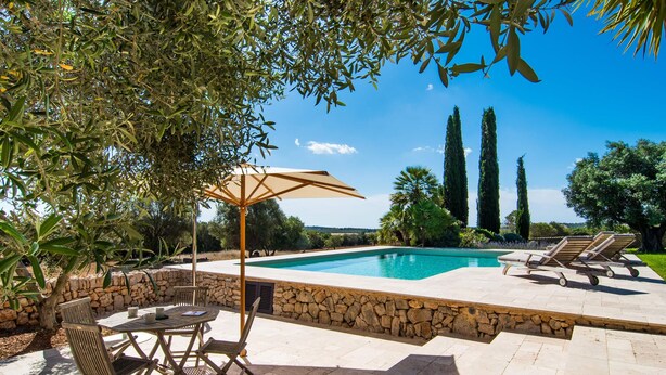 A swimming pool with a stone border, surrounded by lounge chairs and a table with chairs. - Beautiful home in Manacor with private swimming pool, can be inside or outside (Manacor)