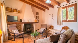 Un saló acollidor amb una llar de foc, seients confortables i una televisió.
