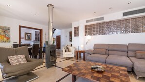 Un salon moderne avec une cheminée, deux canapés, une table basse et, au fond, un coin repas.
