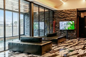 A modern interior with a stone wall, a large TV screen, and a view of a pool. - Gangneung Staymeet Private Pool Villa (Gangneung)
